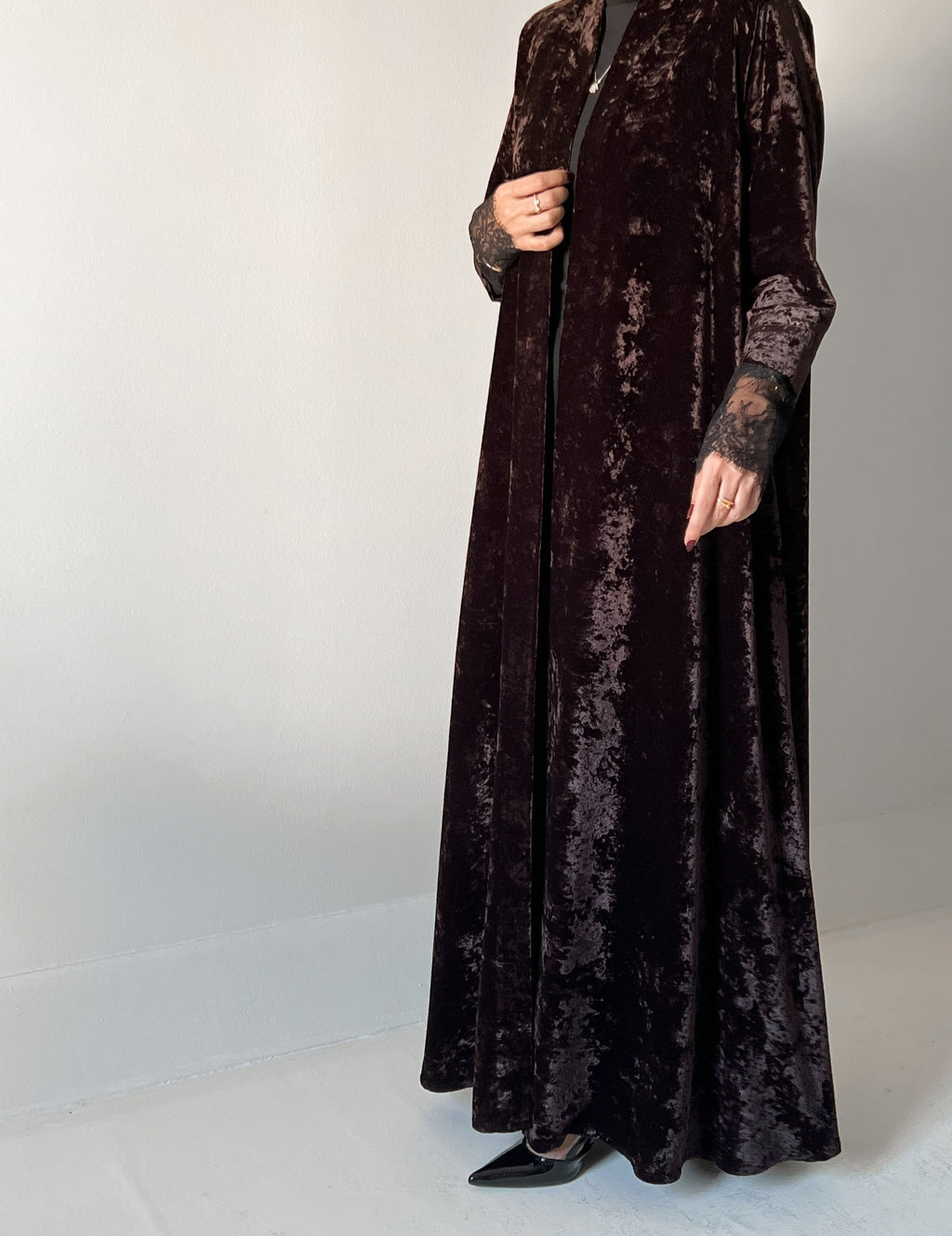 An elegant black abaya crafted from soft velvet fabric, finished with delicate lace detailing on the sleeves for a timeless and feminine look.