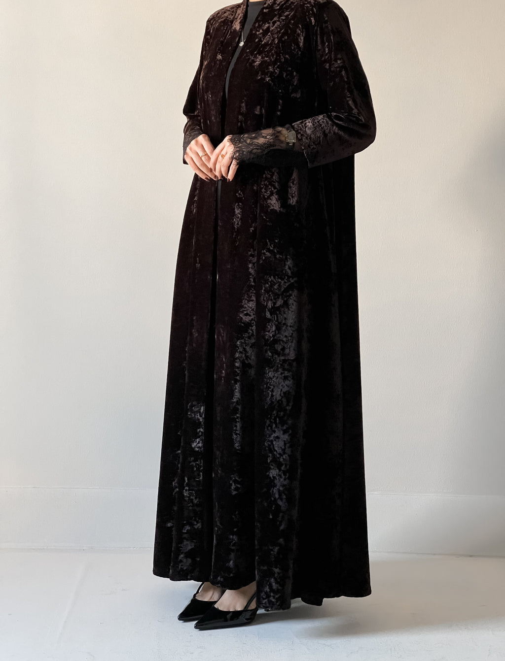 An elegant black abaya crafted from soft velvet fabric, finished with delicate lace detailing on the sleeves for a timeless and feminine look.