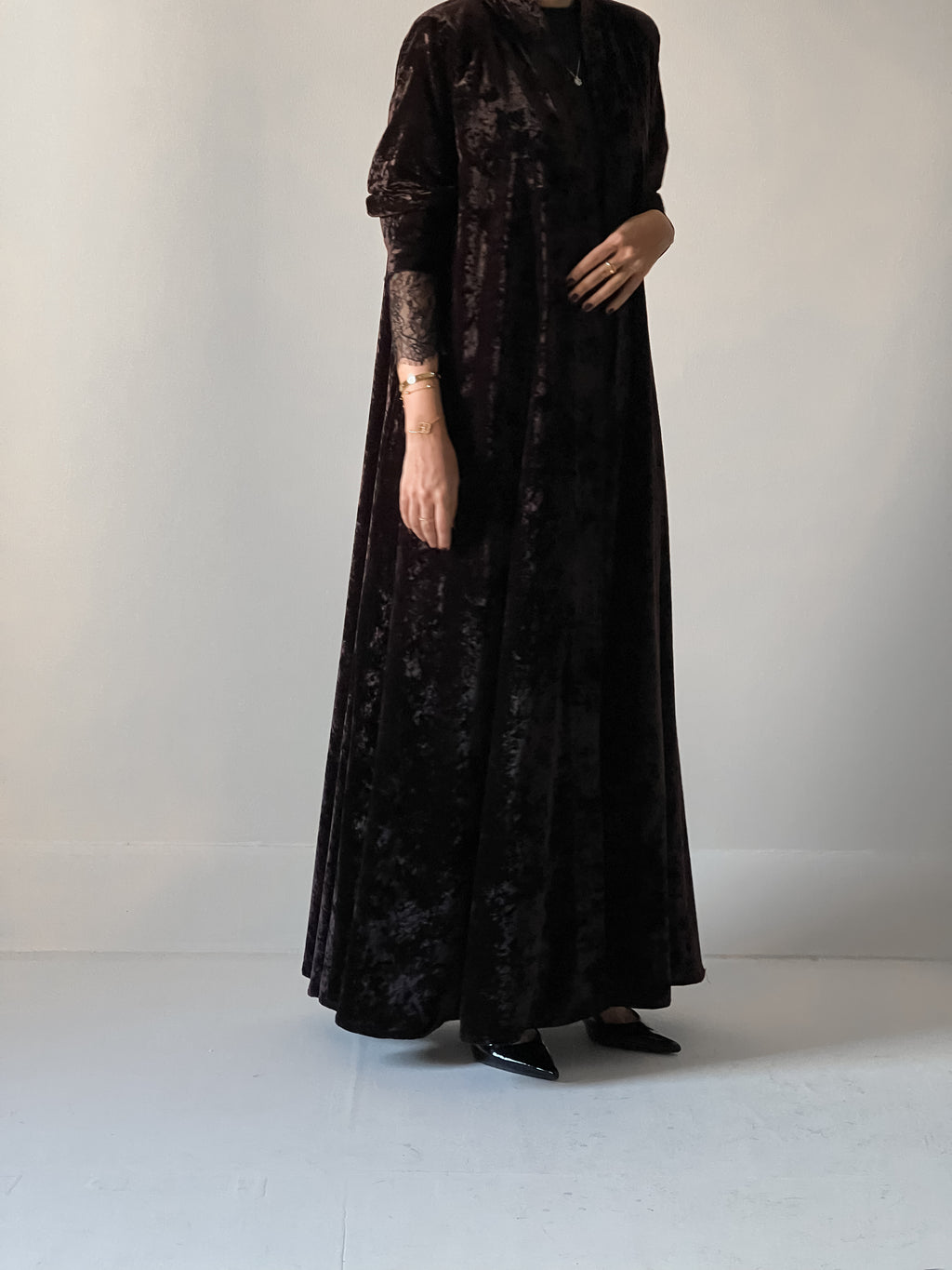 An elegant black abaya crafted from soft velvet fabric, finished with delicate lace detailing on the sleeves for a timeless and feminine look.