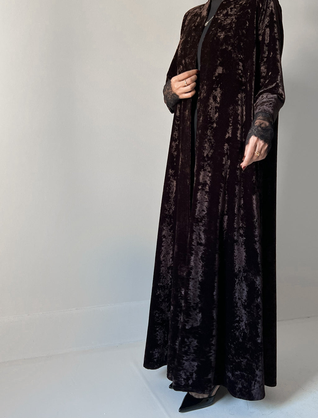 An elegant black abaya crafted from soft velvet fabric, finished with delicate lace detailing on the sleeves for a timeless and feminine look.