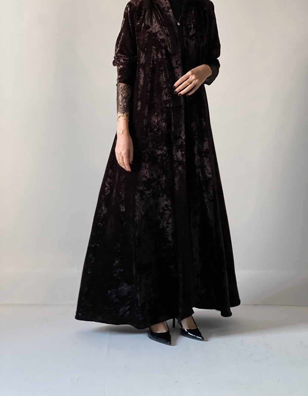 An elegant black abaya crafted from soft velvet fabric, finished with delicate lace detailing on the sleeves for a timeless and feminine look.