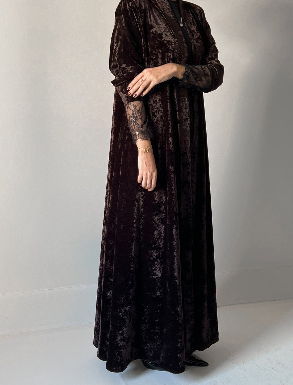 An elegant black abaya crafted from soft velvet fabric, finished with delicate lace detailing on the sleeves for a timeless and feminine look.